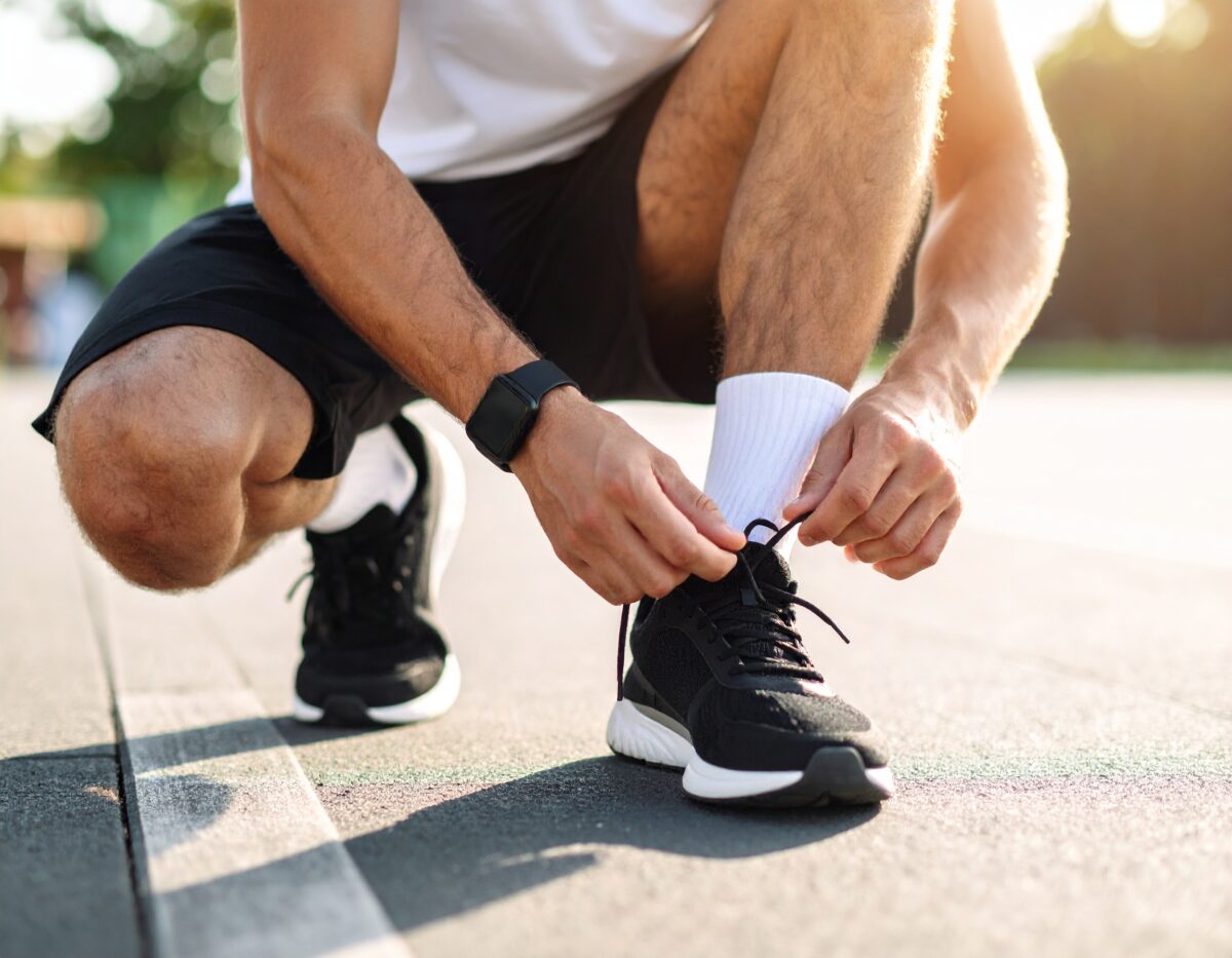 ランニングする男の人、座って靴紐を結ぶ