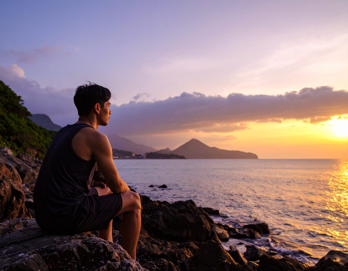 明日の不安を海を見つめて自問自答している様子。男。