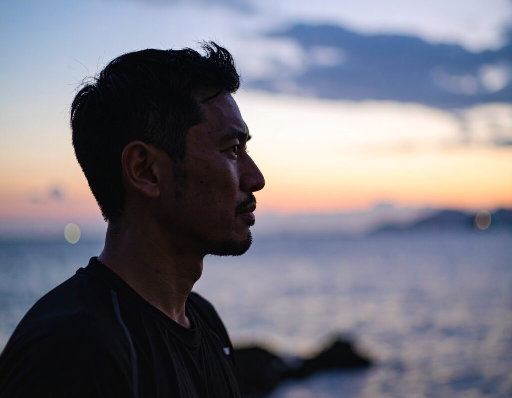明日の不安を海を見つめて自問自答している様子。男。アップ。横顔。