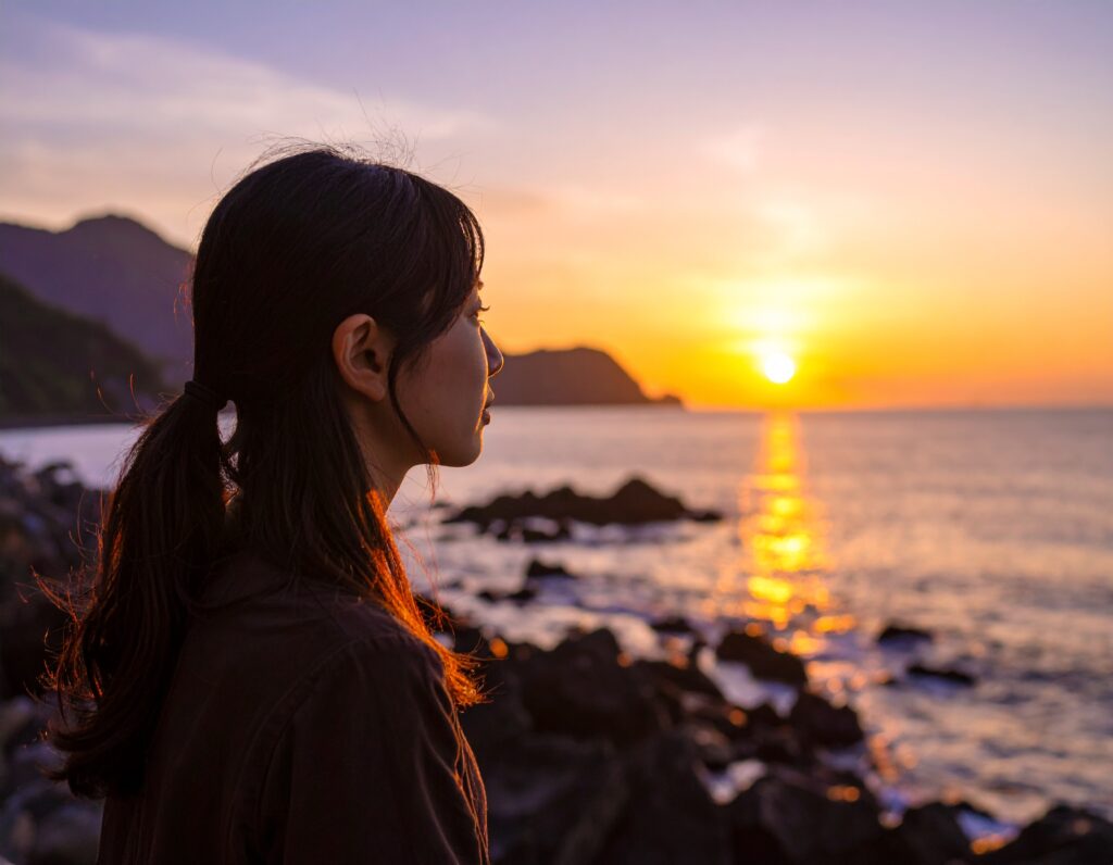 明日の不安を海を見つめて自問自答している様子。女。アップ。横顔。